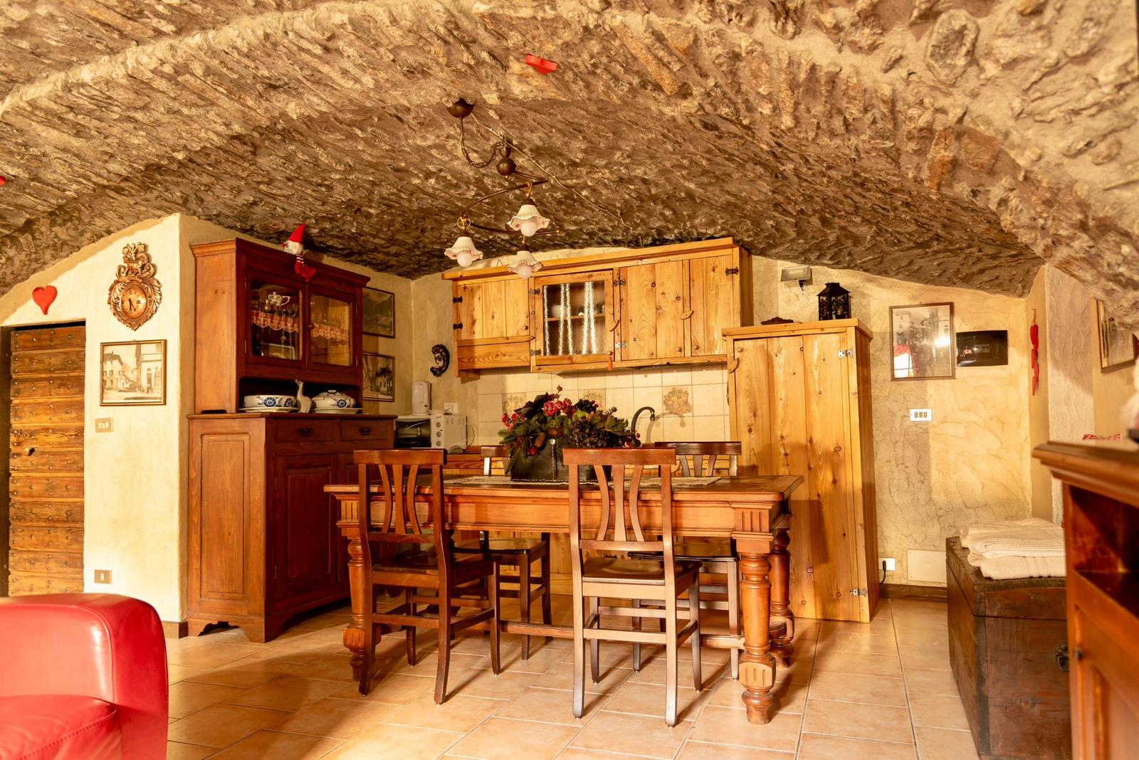 Sala da pranzo con tavolo in legno massello sotto la volta in pietra
