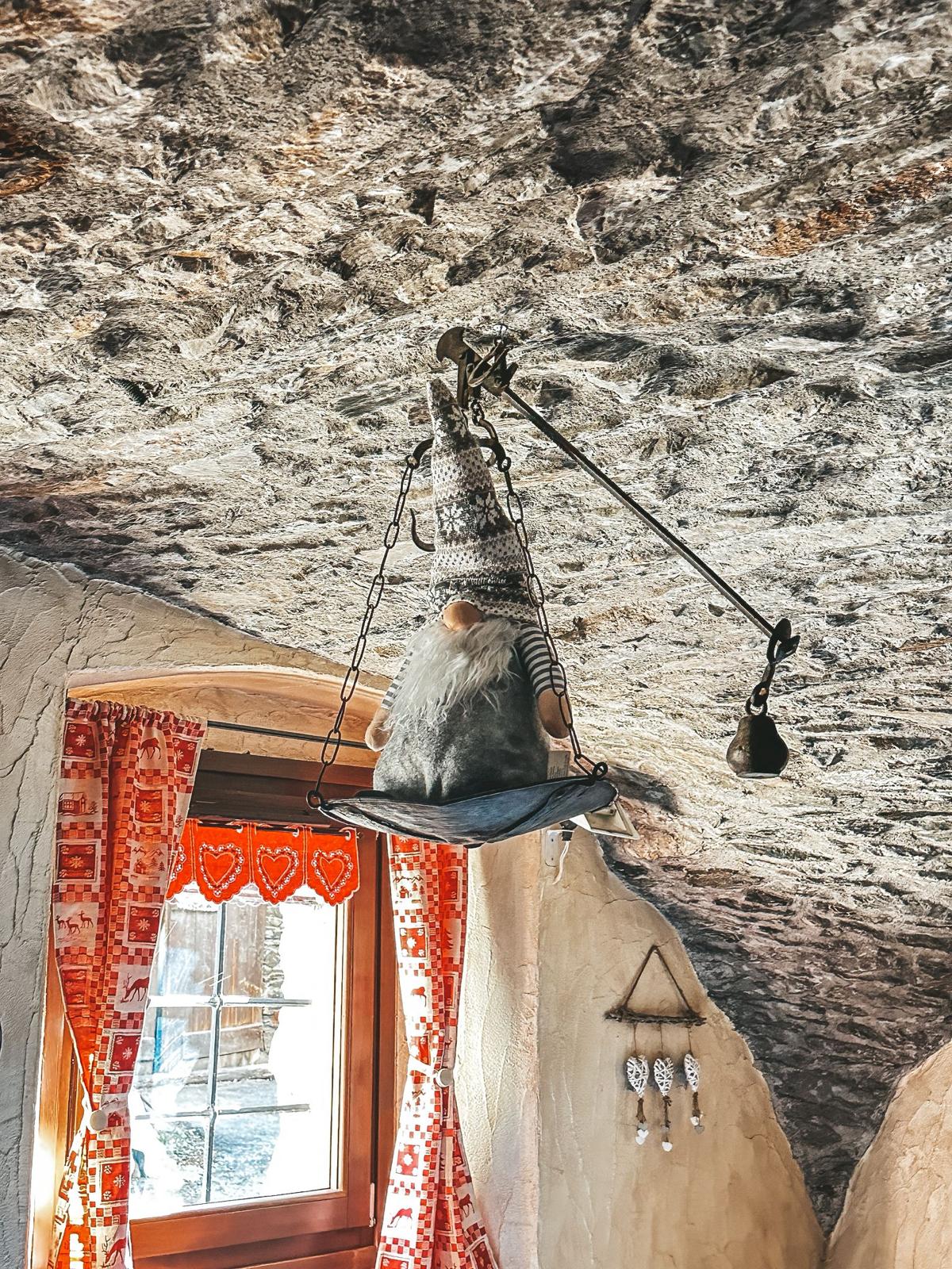 Lampada artigianale con gnomo sospesa sotto il soffitto in pietra