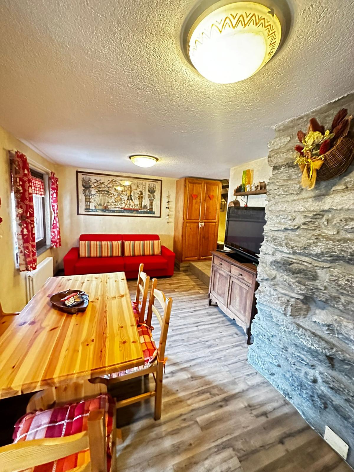 Sala da pranzo con tavolo in legno chiaro e divano rosso