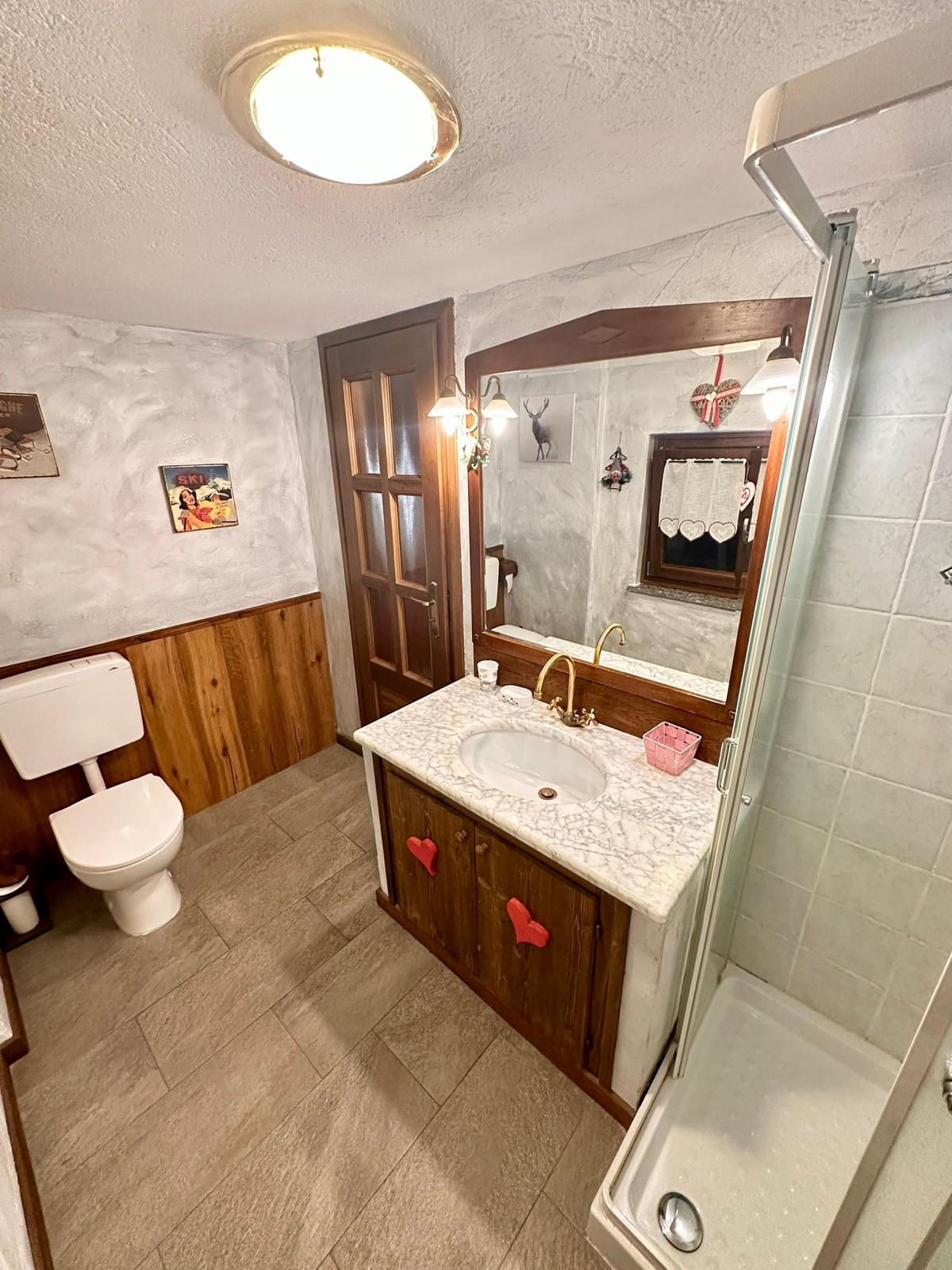 Bagno con mobile in legno, lavabo in marmo e box doccia