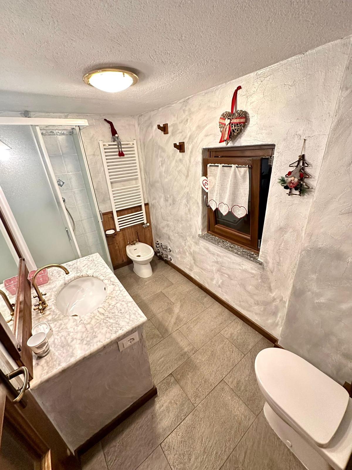 Bagno con doccia, lavabo in marmo e decorazioni a cuore