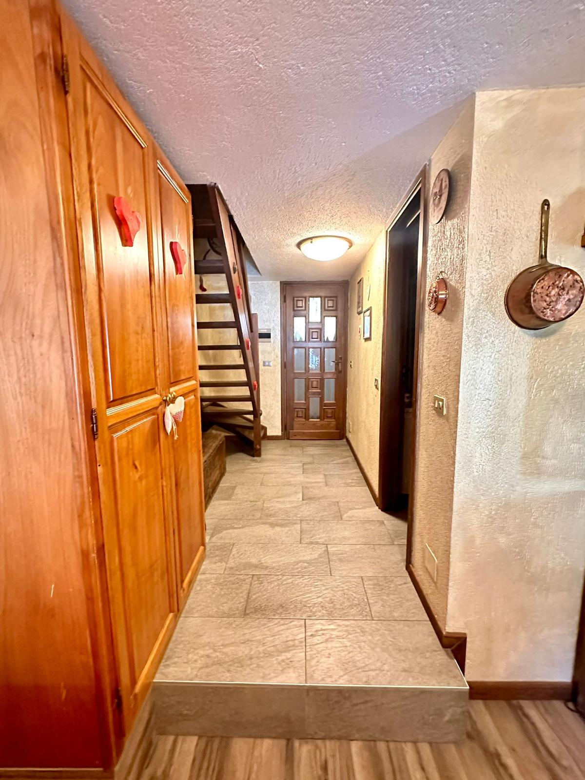 Corridoio d'ingresso con scala in legno e armadio con cuori rossi