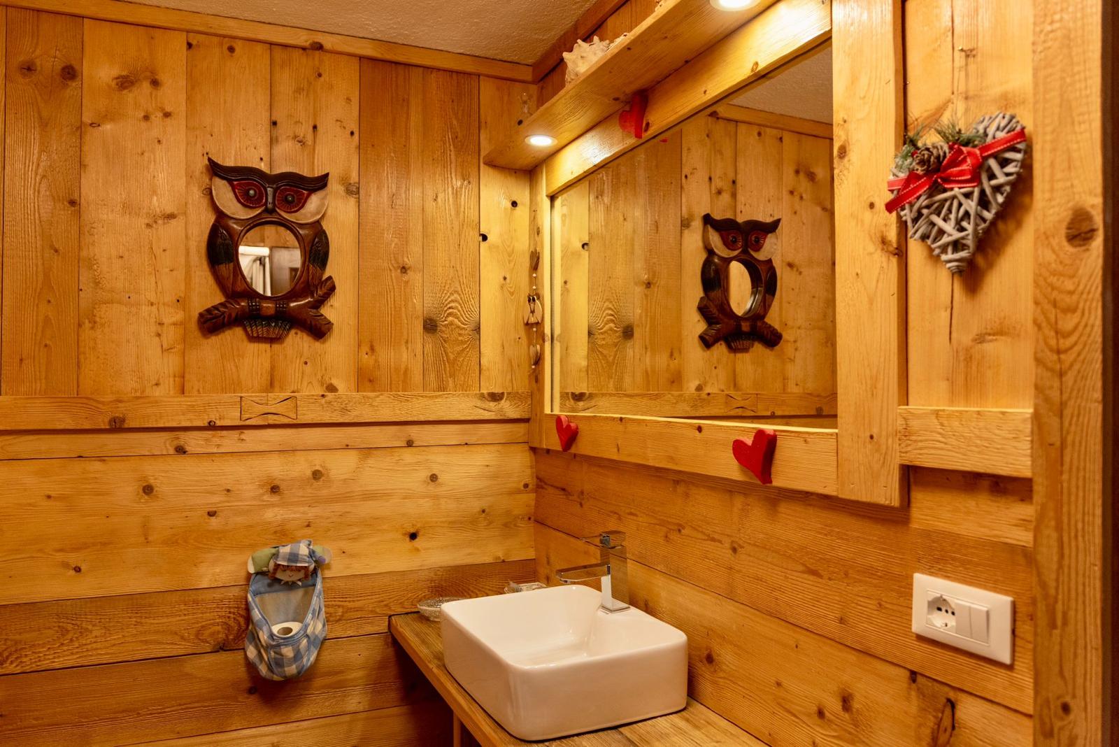 Bagno rivestito in legno di abete con specchio e lavabo moderno