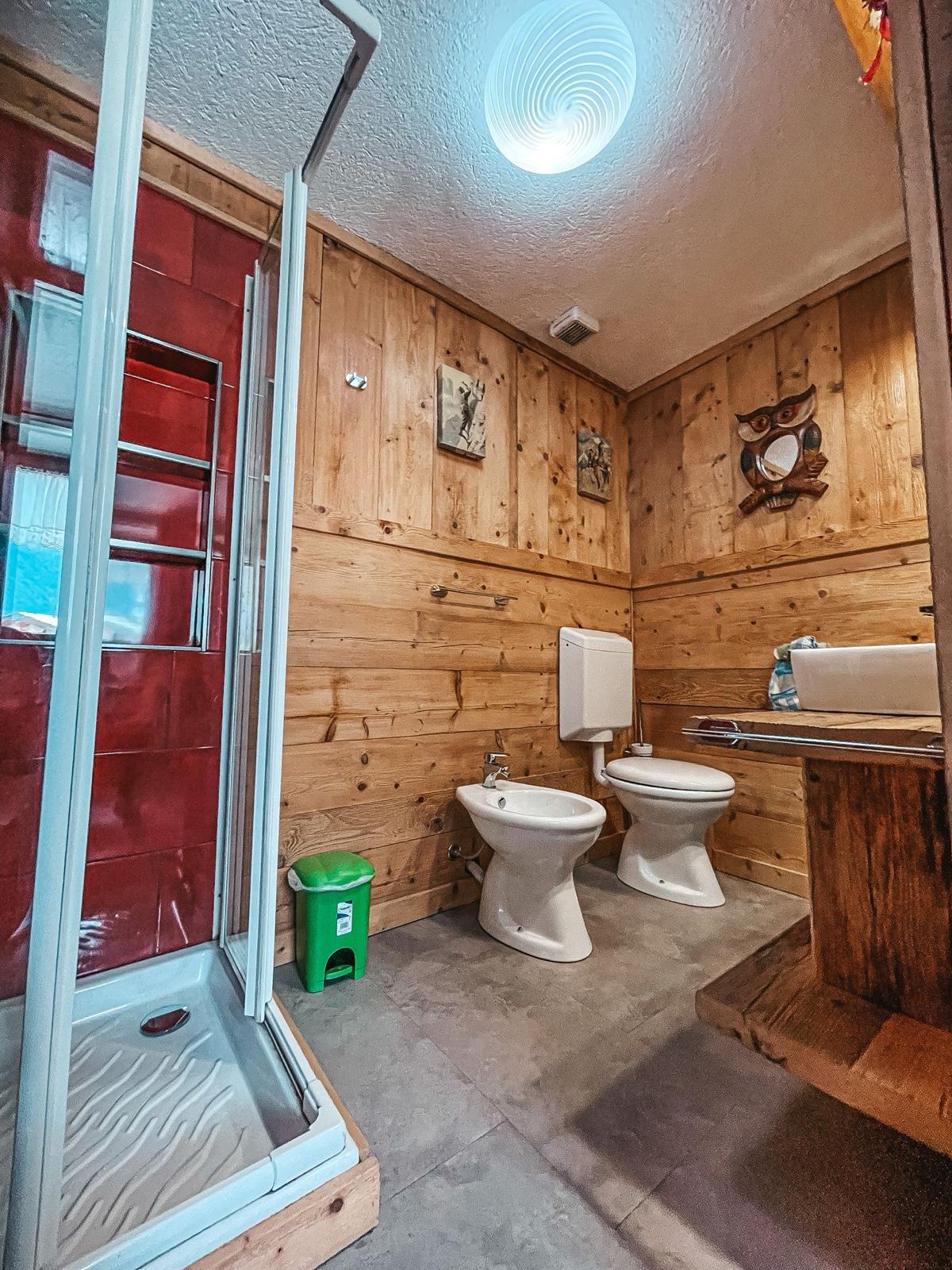 Secondo bagno con doccia, bidet e pareti in legno naturale
