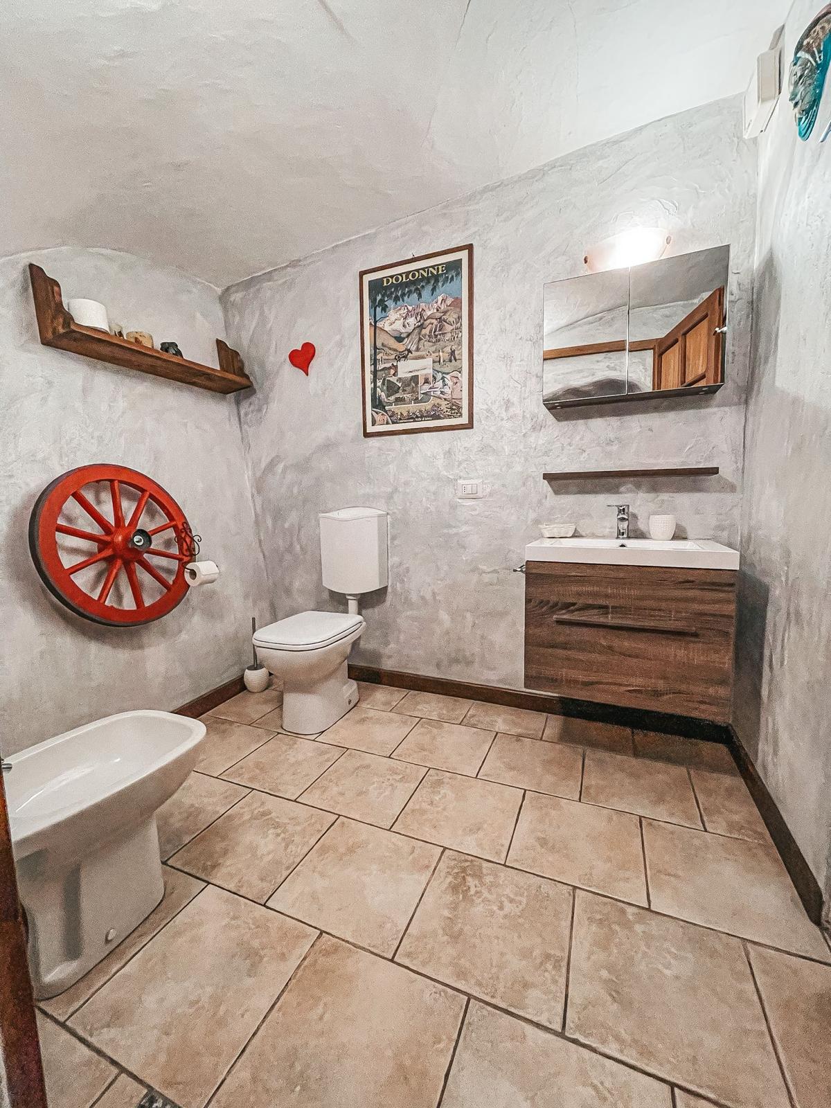 Bagno moderno con ruota di carro rossa e mobile lavabo in legno