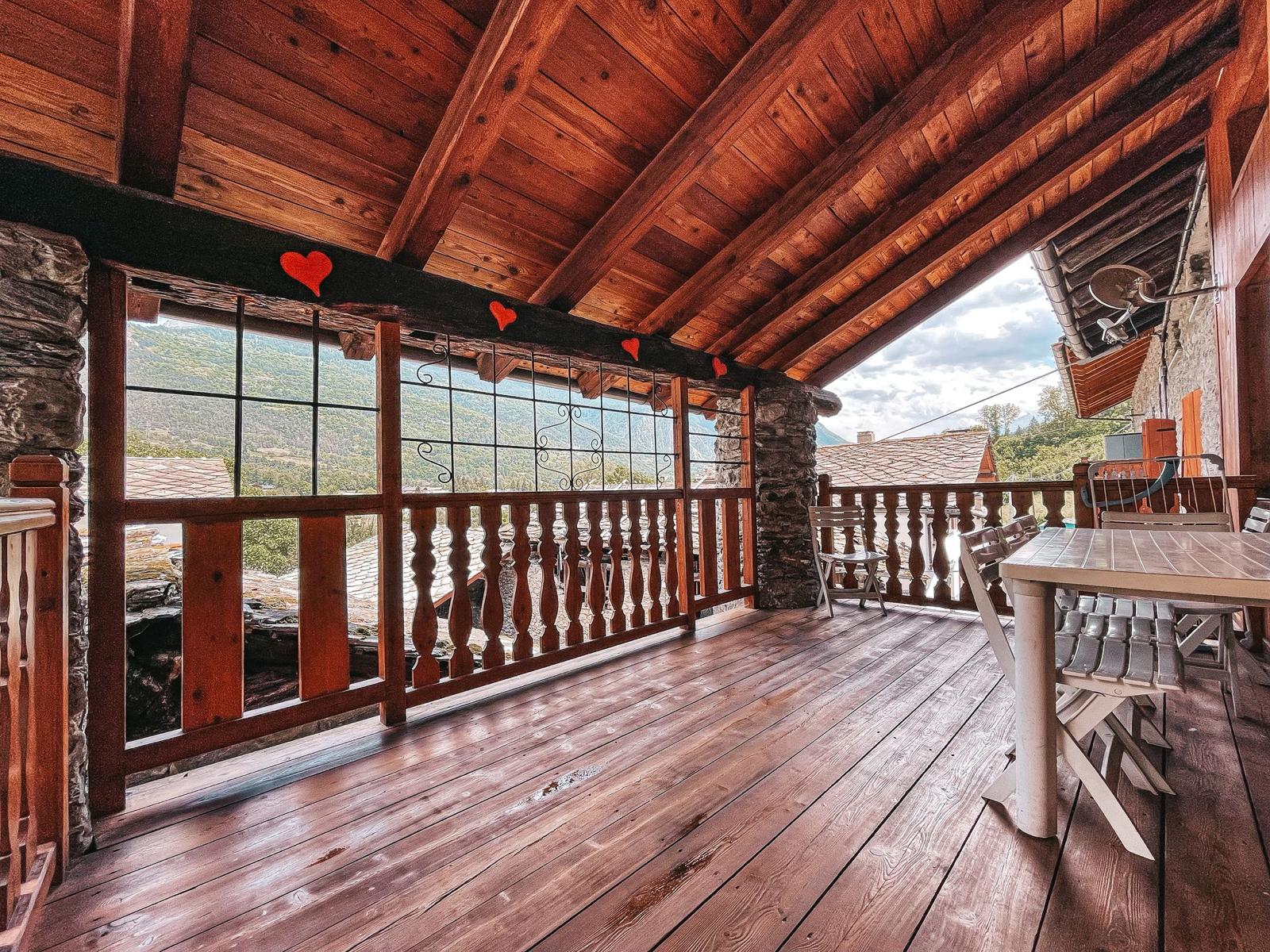 Terrazza coperta in legno con tavolo e vista sulle montagne