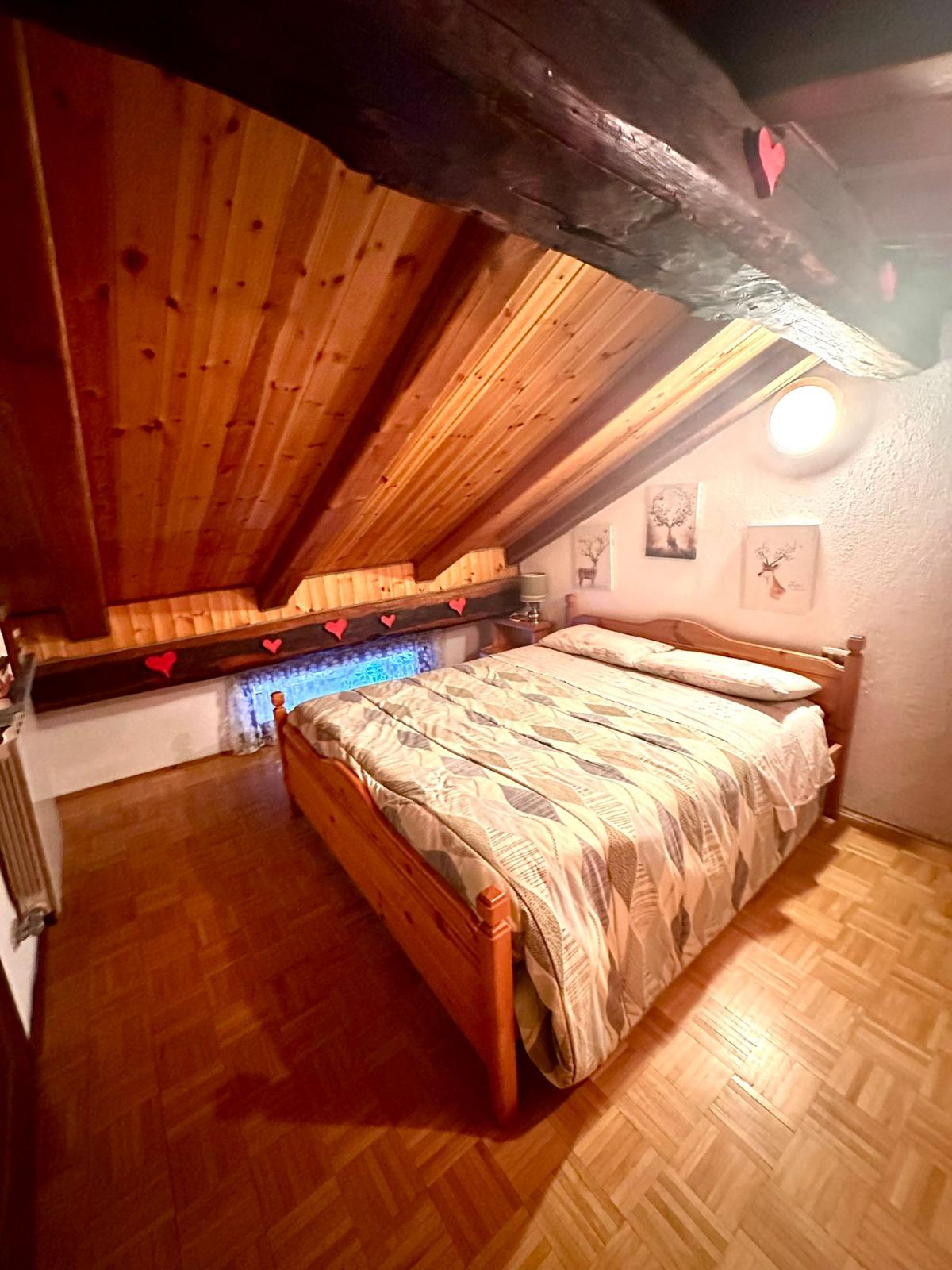 Seconda camera in mansarda con perlinato in legno e cuori rossi